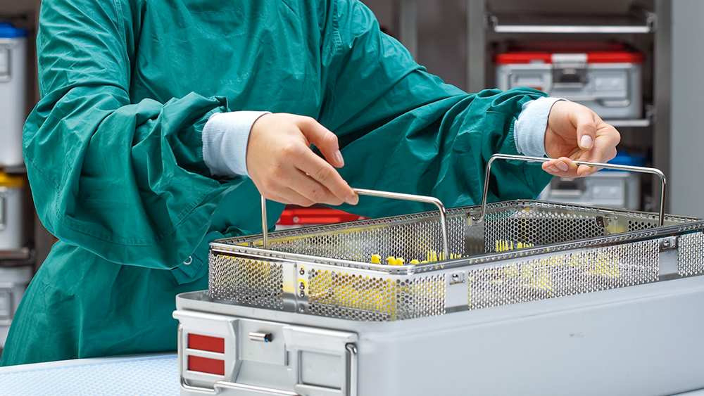 CSSD employee lifts a basket with instruments out of a sterile container