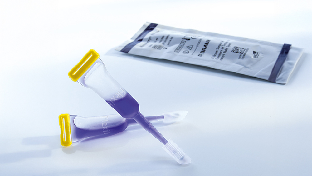 Two skin closure adhesive tubes with blue skin adhesive on a grey ground, behind you can see a peel off blister package of the skin adhesive.
