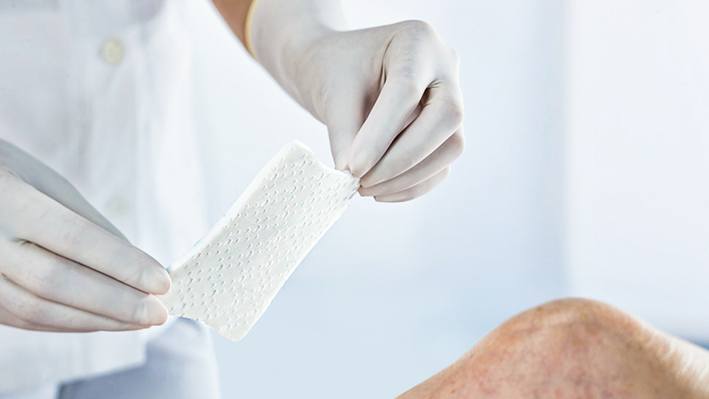 a plaster is being stuck on a knee with two gloved hands