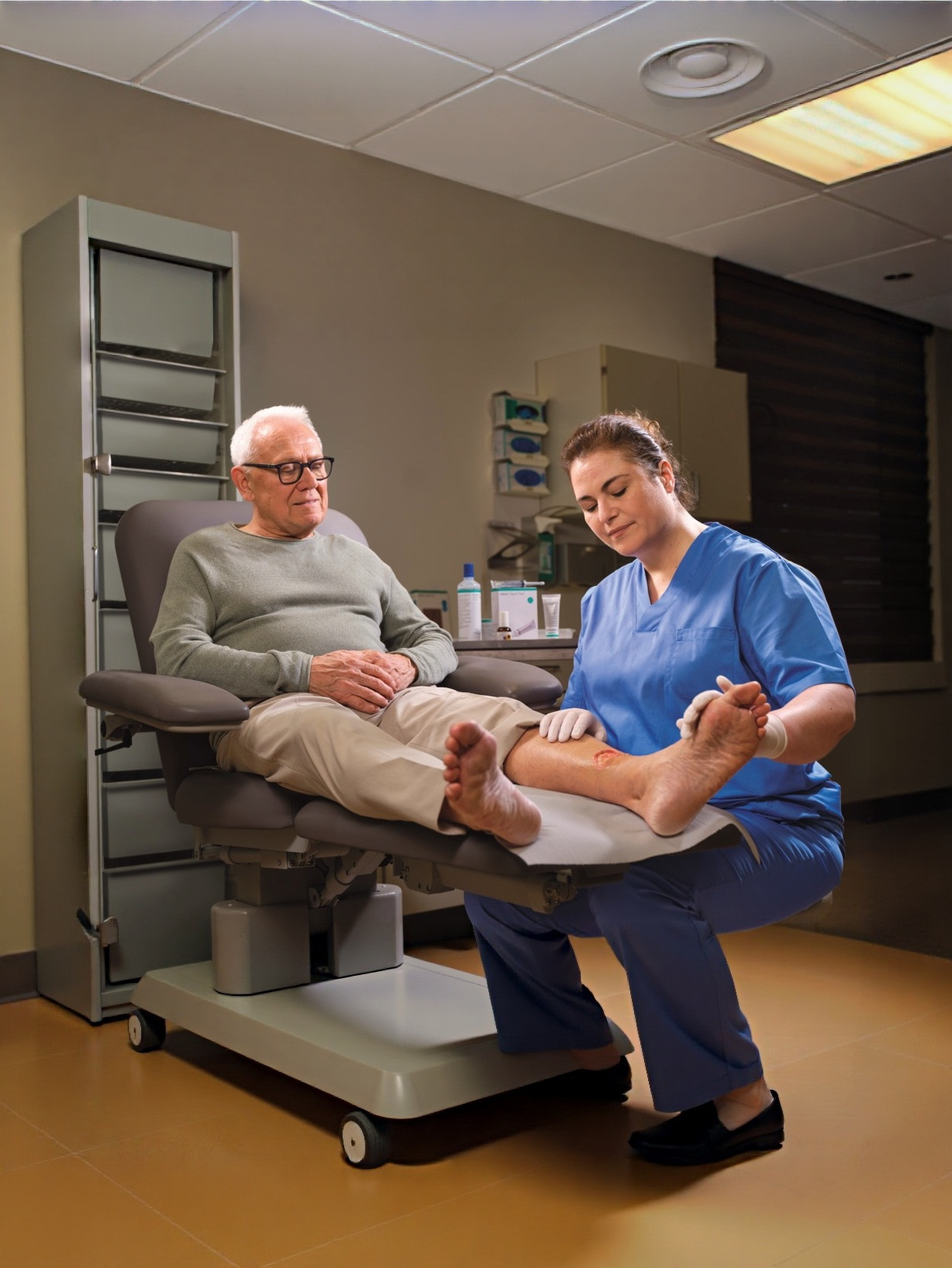 mage showing a close-up of a leg with an open wound being treated with Askina Calgitrol Paste dressing, being applied by a nurse. The wound appears inflamed with surrounding redness, highlighting a medical care or wound treatment context.