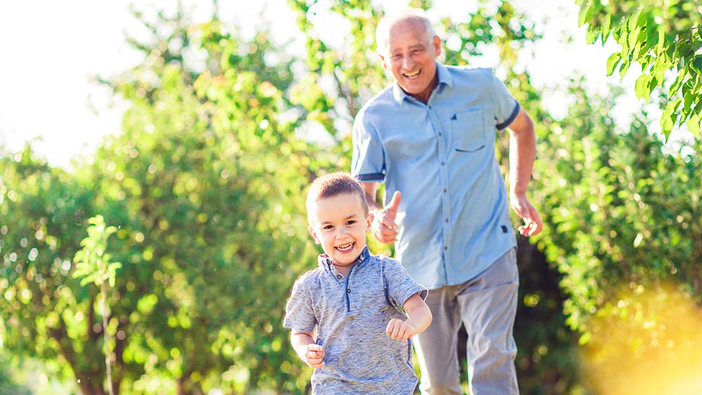 Grandfather runs after his little grandson in the park