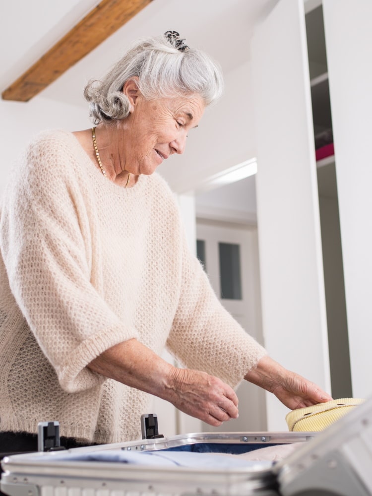 elderly woman preparing suitcase