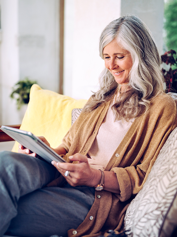 A woman sits on the sofa and reads on her tablet