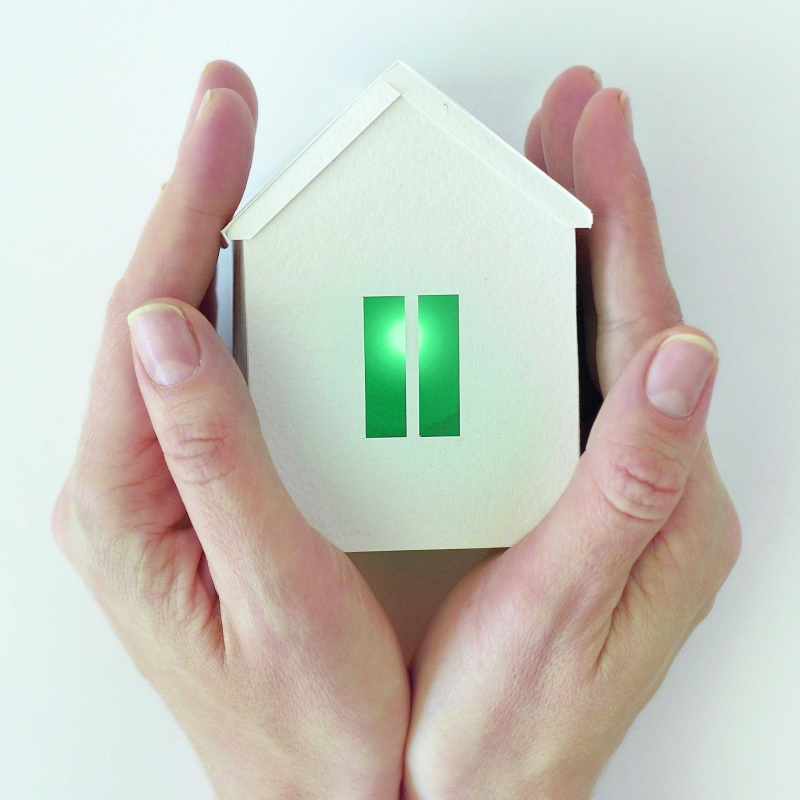 Two female hands embrace a small model house from both sides.