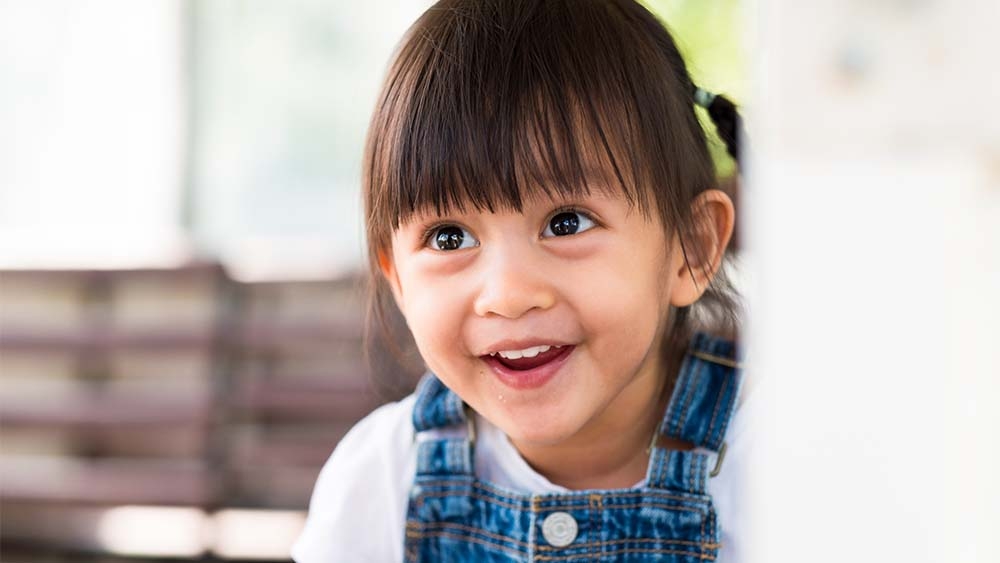 A joyful little child looks up, her smile radiating happiness and innocence. 