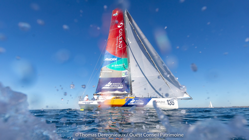 A huge yacht in the water with a colorful sail