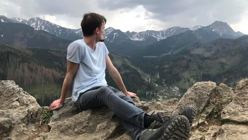 Man who sits on a mountain and looks to the valley