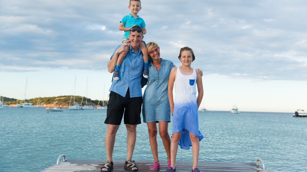 Husband and wife with two children who stand on a bridge